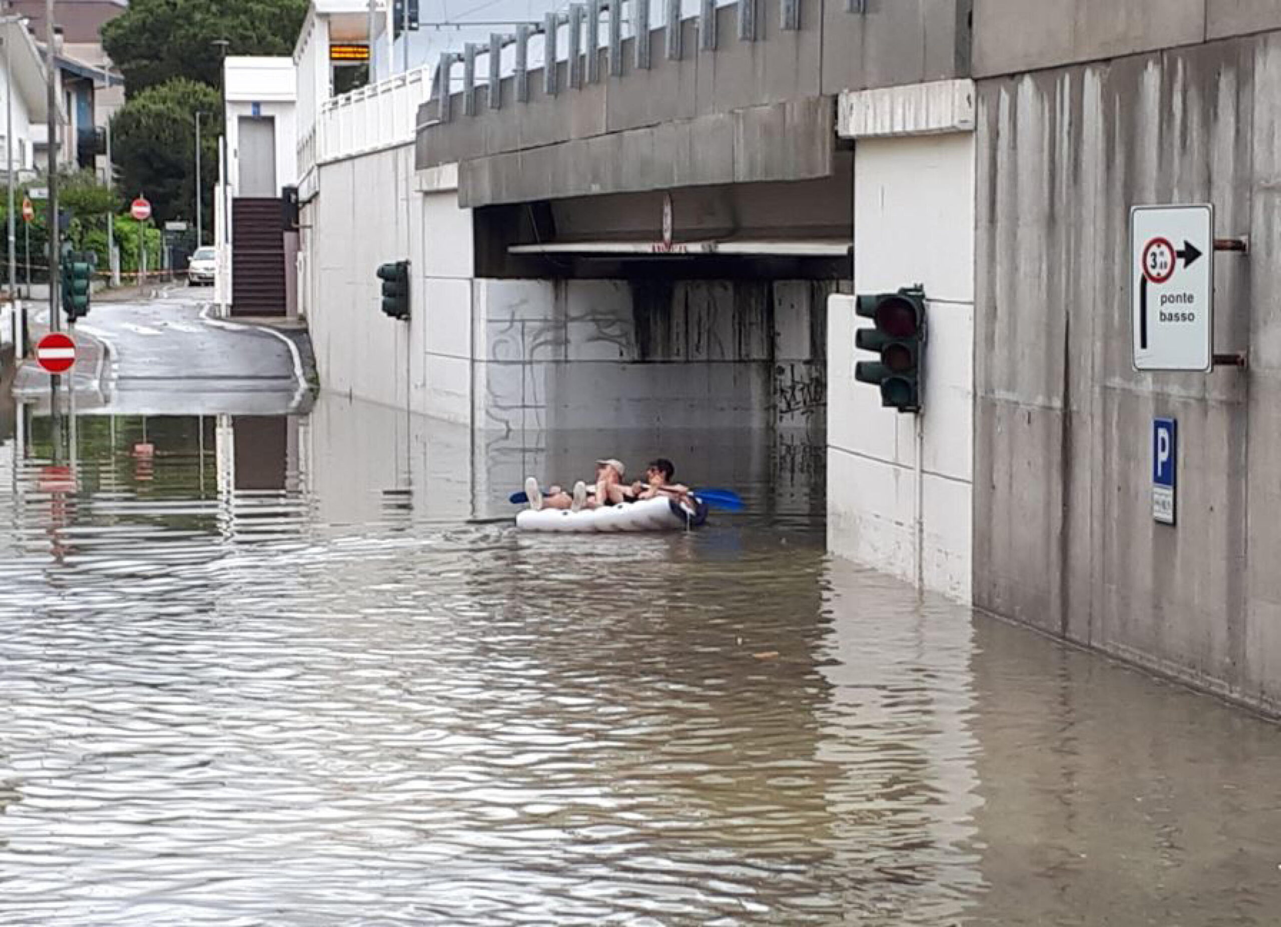 Due persone su un materassino in una strada allagata a causa del maltempo