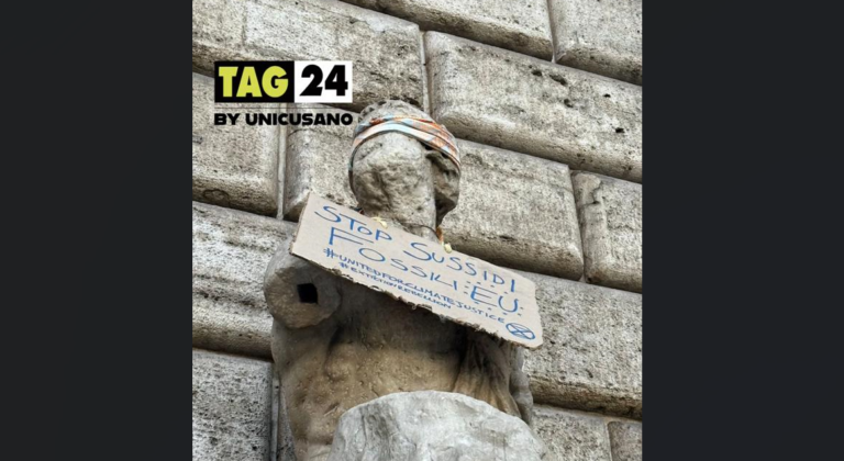 Cartello sulla Statua di Pasquino a Roma: la scritta "Stop ai sussidi fossili" è una freccia scoccata dagli attivisti per il clima di Extinction Rebellion | FOTO